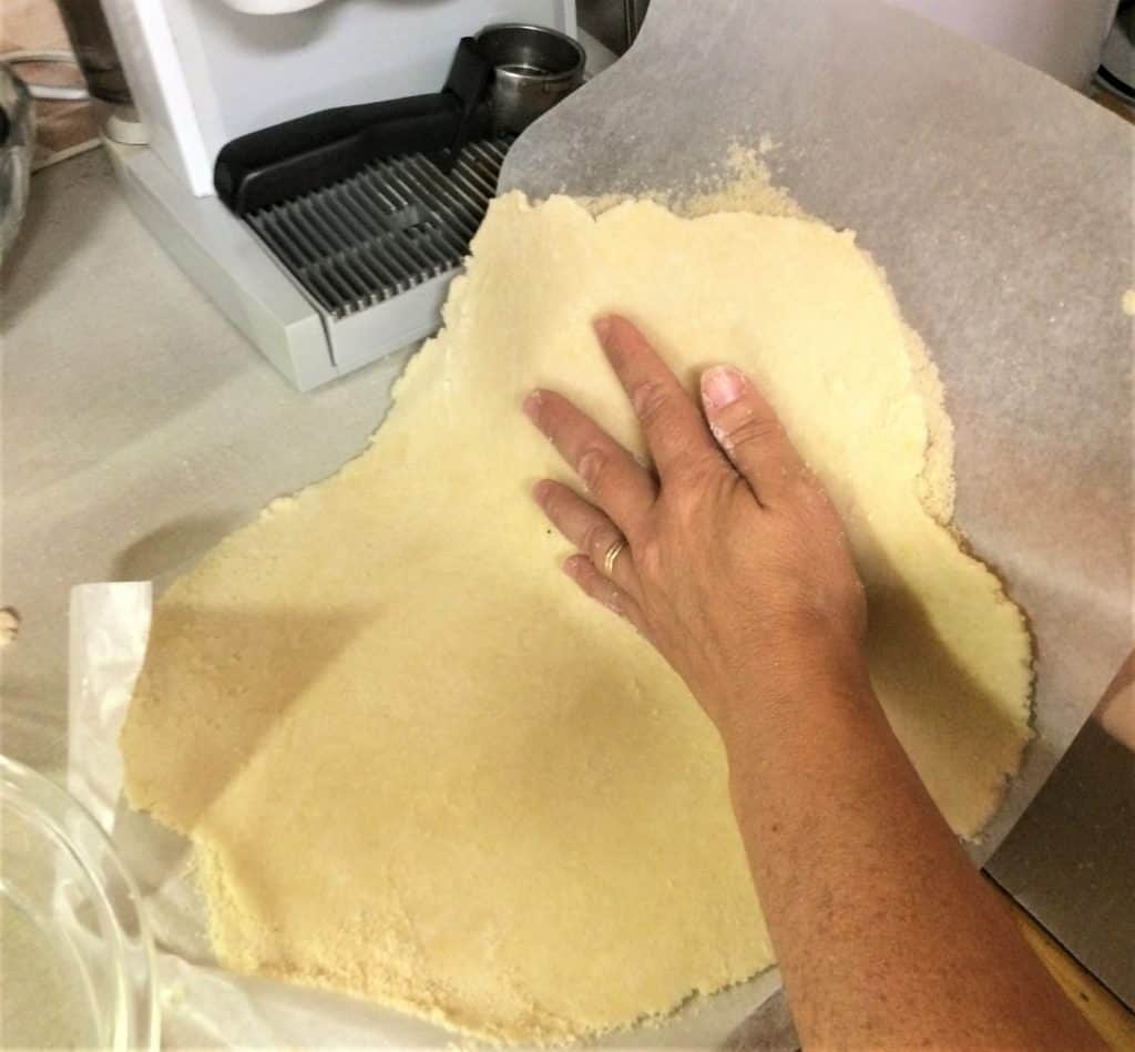 Sandwich the  dough and wax paper between your hands.