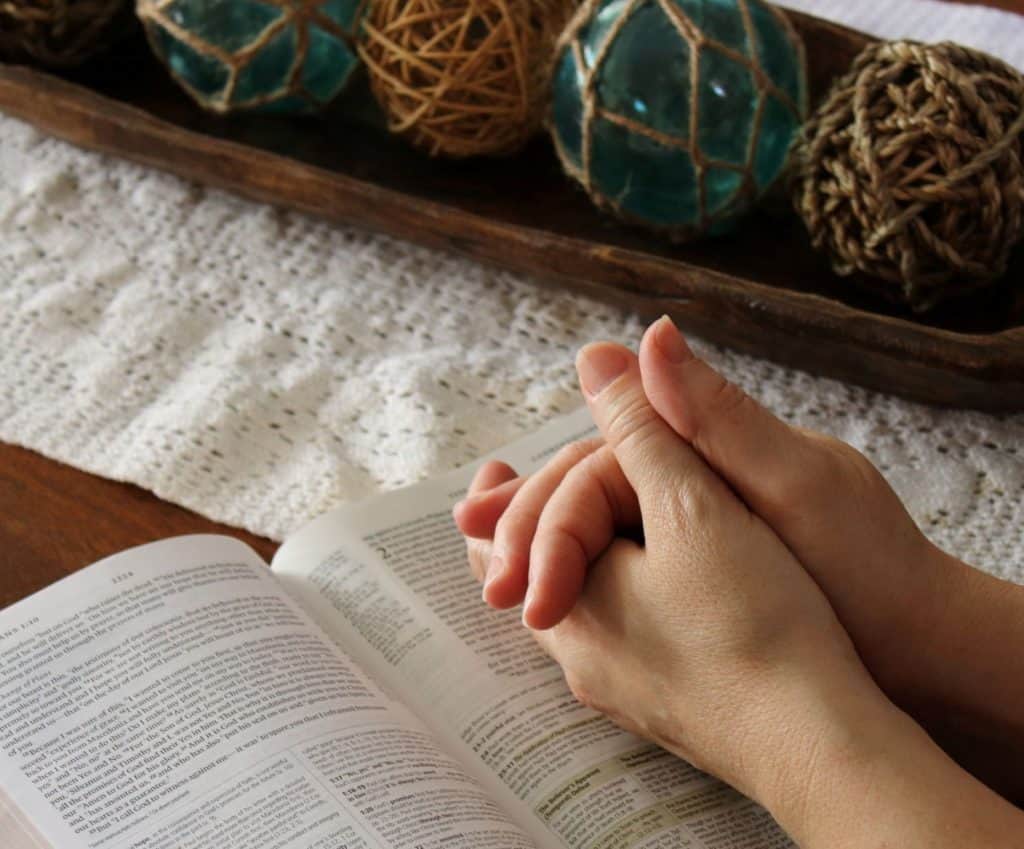 Hands in prayer over a Bible